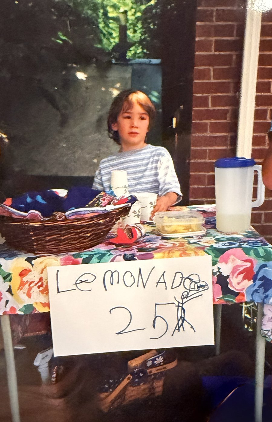 Owen as a young child running a lemonade stand outside a brick house